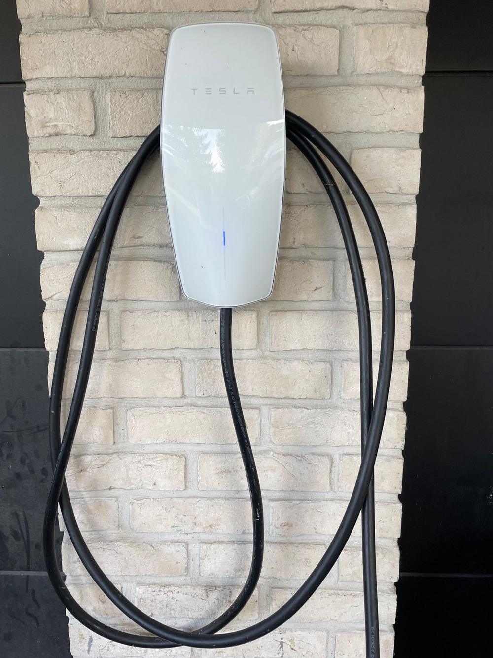 Borne Tesla Wall Connector fixée sur un pilier en brique claire